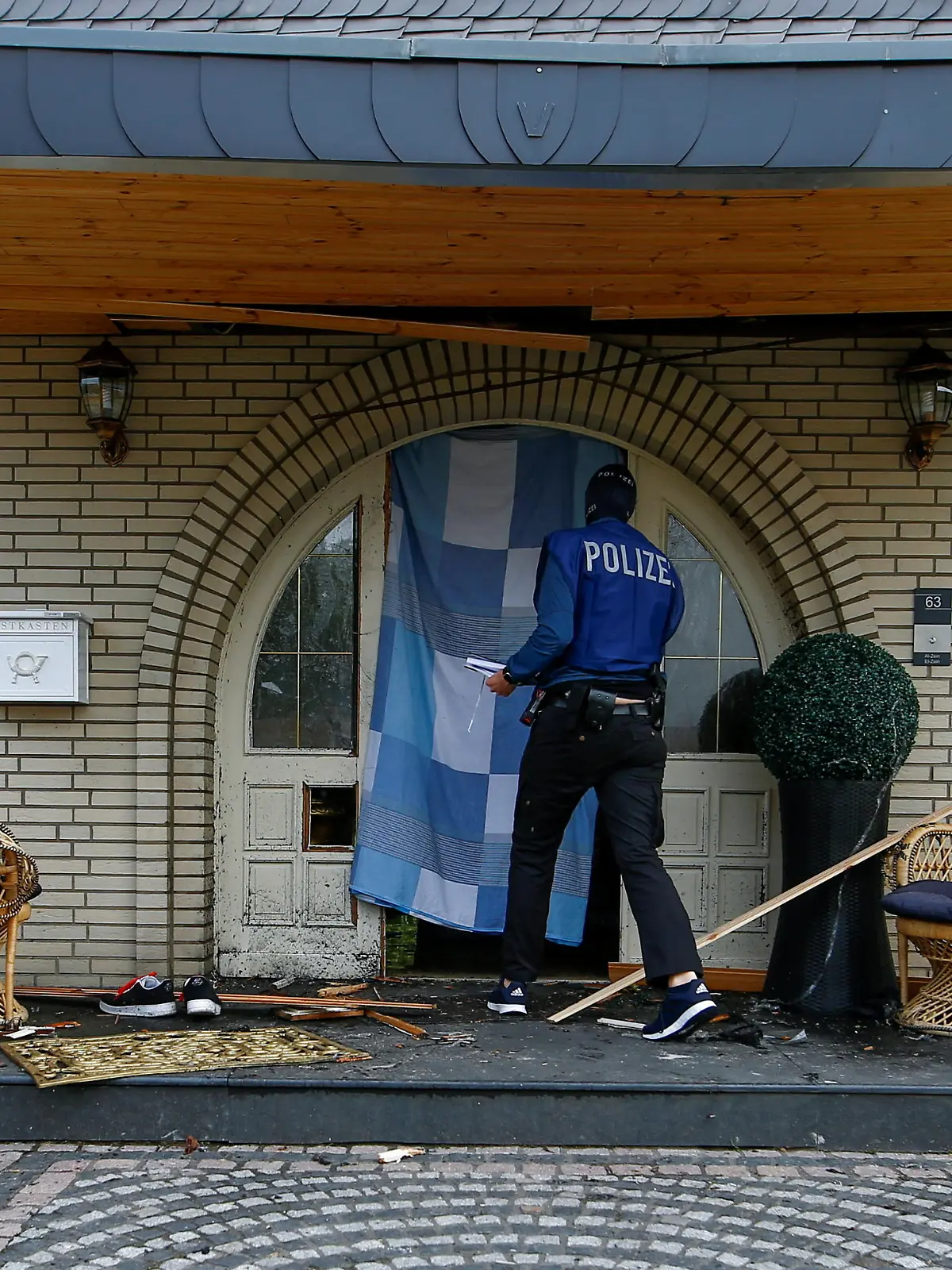 A German police officer stands in front of a door to a villa that was opened with explosives by a SWAT team during a raid in the clan milieu in Leverkusen, Germany, June 8, 2021. REUTERS/Thilo Schmuelgen