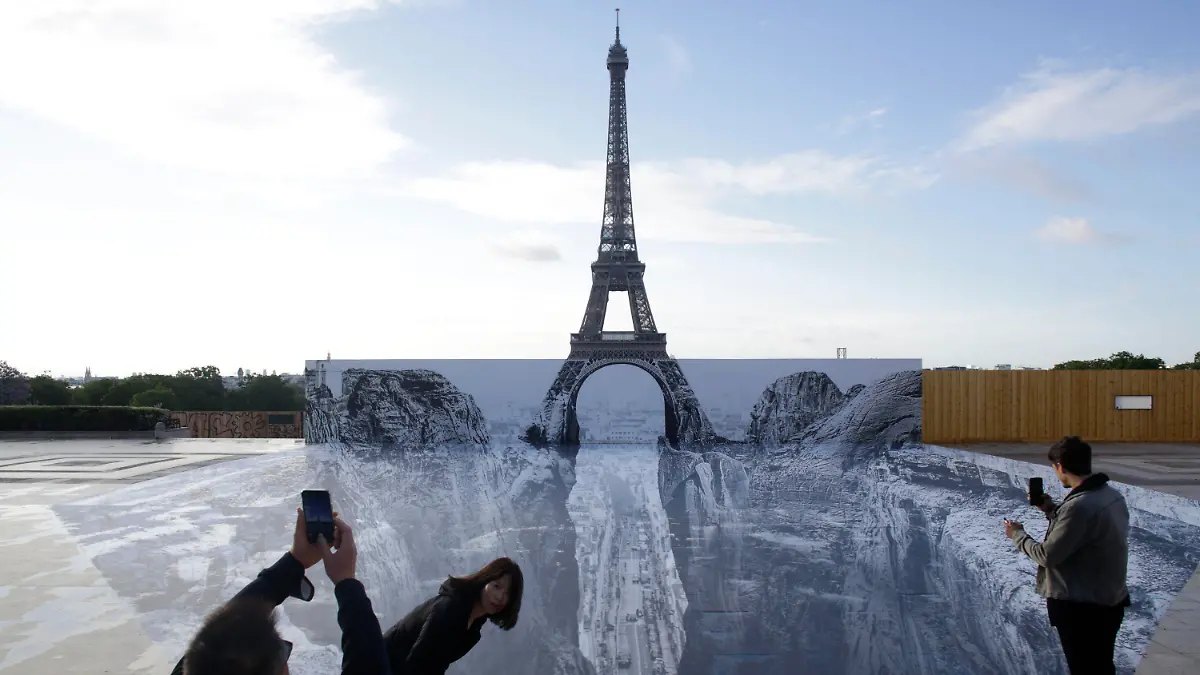 19.05.2021, Frankreich, Paris: Menschen fotografieren Kunstwerke des französischen Fotografen und Streetart-Künstlers JR, die auf dem Trocadero-Platz vor dem Eiffelturm ausgestellt sind. Foto: Thibault Camus/AP/dpa - ACHTUNG: Nur zur redaktionellen Verwendung im Zusammenhang mit einer Berichterstattung über den Künstler JR und nur mit vollständiger Nennung des vorstehenden Credits +++ dpa-Bildfunk +++