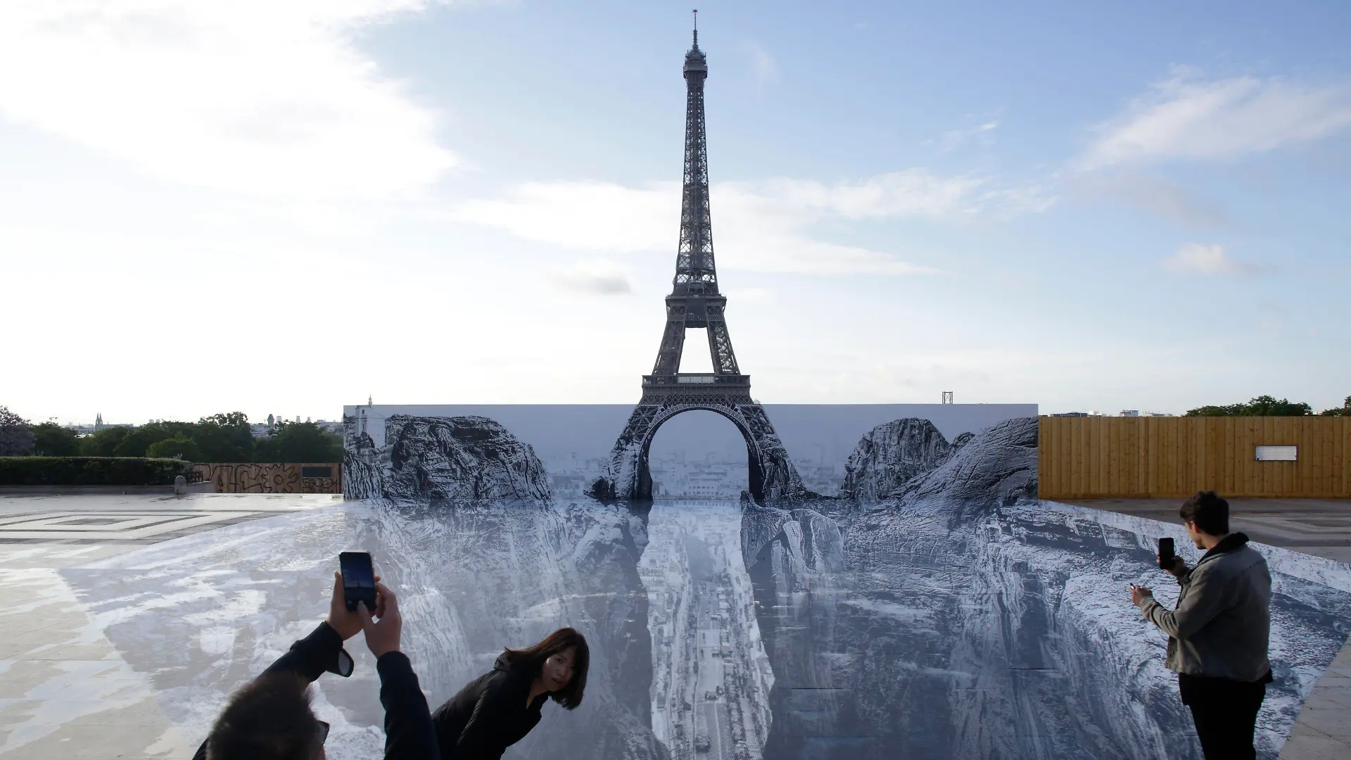 19.05.2021, Frankreich, Paris: Menschen fotografieren Kunstwerke des französischen Fotografen und Streetart-Künstlers JR, die auf dem Trocadero-Platz vor dem Eiffelturm ausgestellt sind. Foto: Thibault Camus/AP/dpa - ACHTUNG: Nur zur redaktionellen Verwendung im Zusammenhang mit einer Berichterstattung über den Künstler JR und nur mit vollständiger Nennung des vorstehenden Credits +++ dpa-Bildfunk +++