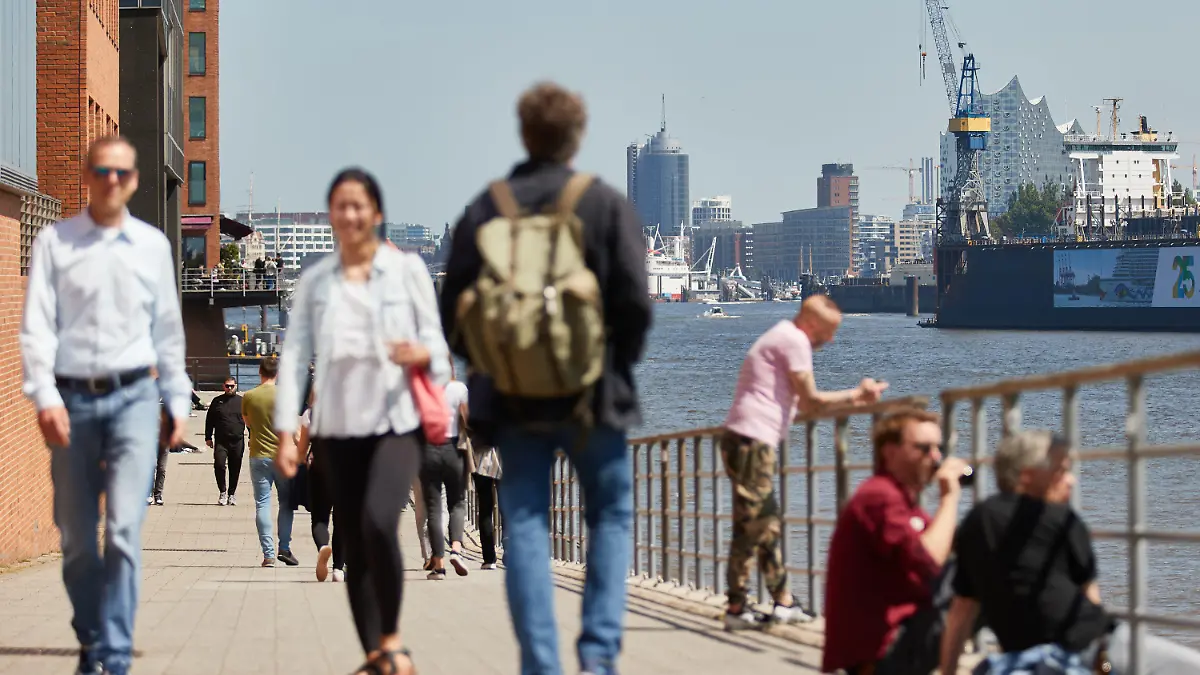 30.05.2021, Hamburg: Menschen gehen bei Sonnenschein und angenehm warmen Temperaturen am Holzhafen spazieren. Im Hintergrund ist die Elbphilharmonie zu sehen. Foto: Georg Wendt/dpa +++ dpa-Bildfunk +++