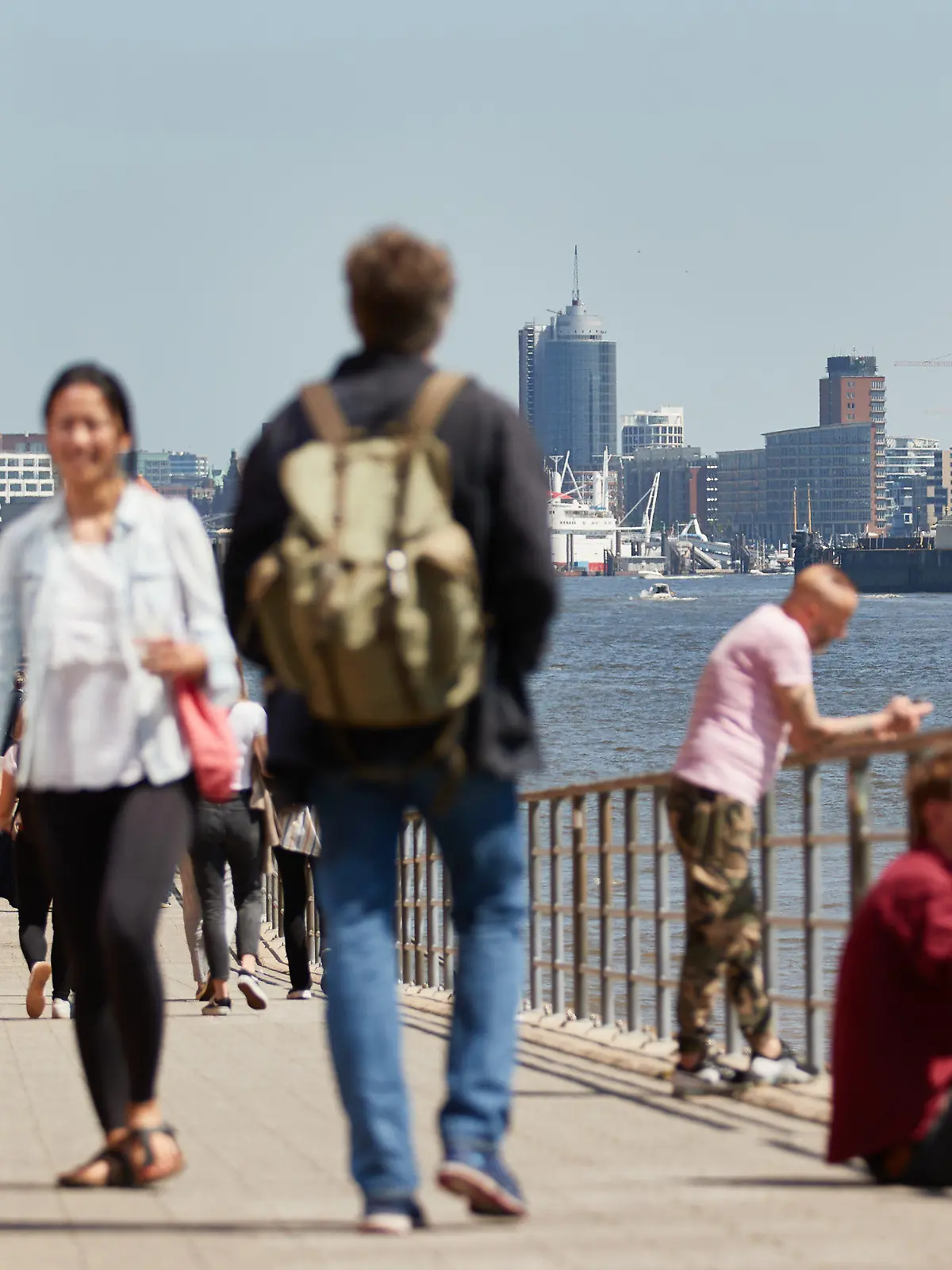 30.05.2021, Hamburg: Menschen gehen bei Sonnenschein und angenehm warmen Temperaturen am Holzhafen spazieren. Im Hintergrund ist die Elbphilharmonie zu sehen. Foto: Georg Wendt/dpa +++ dpa-Bildfunk +++