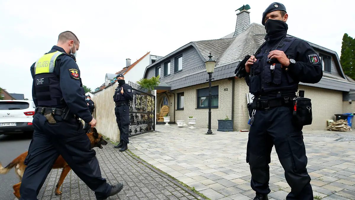 A German police officer and his sniffing dog enter the yard of a villa following a police raid in the clan milieu, in Leverkusen, Germany, June 8, 2021.  REUTERS/Thilo Schmuelgen