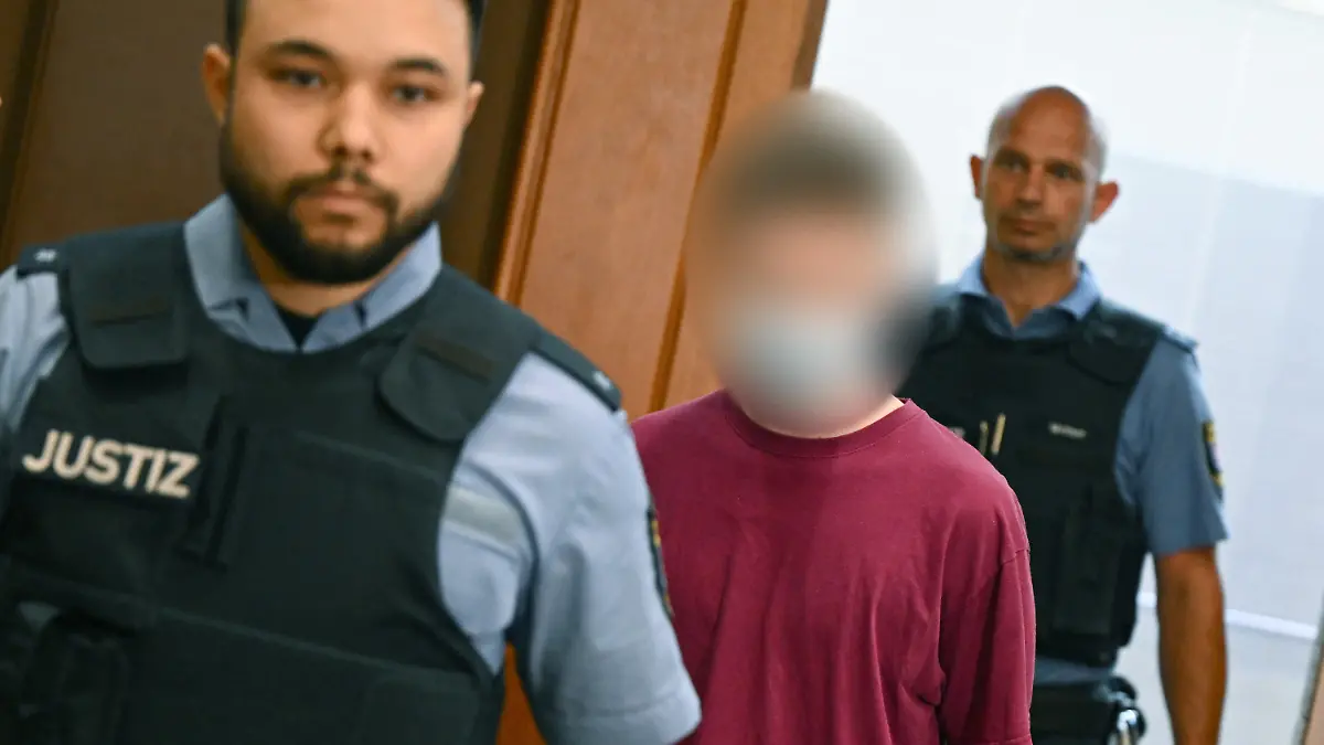 02.08.2022, Hessen, Frankfurt/Main: Der Angeklagte Marvin E. (M) kommt in Begleitung von Justizbeamten zum Prozessauftakt in den Gerichtssaal des Oberlandesgerichts. Die Bundesanwaltschaft wirft dem Mann aus Nordhessen die versuchte Gründung einer terroristischen Vereinigung und die Vorbereitung einer schweren staatsgefährdenden Gewalttat vor. Marvin E. soll aus rechtsextremistischen Motiven Anschläge mit Schusswaffen und Sprengsätzen geplant und vorgehabt haben, eine Terrororganisation zu bilden. Foto: Arne Dedert/dpa - ACHTUNG: Angeklagter auf Anweisung des Gerichts gepixelt! +++ dpa-Bildfunk +++