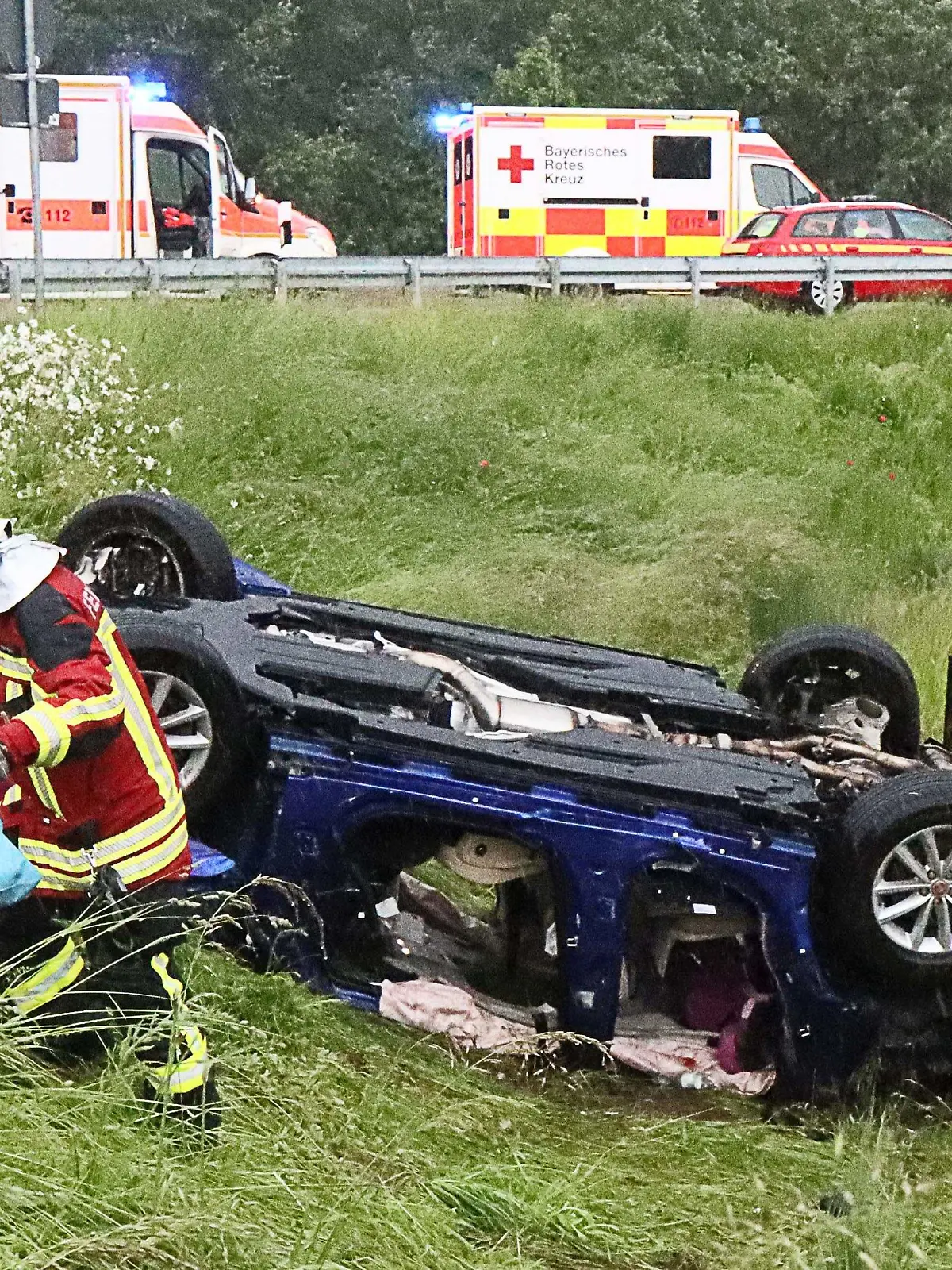 06.06.2021, Baden-Württemberg, Jettingen-Scheppach: Ein Retter holt persönliche Dinge einer Familie aus dem Wrack von deren Fahrzeug an der A8. Das Fahrzeug geriet bei teils schwerem Regen ins Schleudern, kam dann von der Fahrbahn ab, überschlug sich mehrfach und blieb schließlich auf dem Dach liegen. Die Insassen, eine fünfköpfige Familie, darunter drei Kinder, sind verletzt worden. Foto: Mario Obeser/dpa +++ dpa-Bildfunk +++