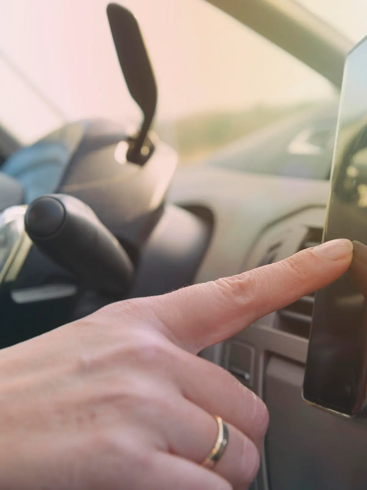 Eine Frau, von der man nur die Hand erkennen kann, benutzt während der Fahrt ihr Handy bzw. mobiles Endgerät.