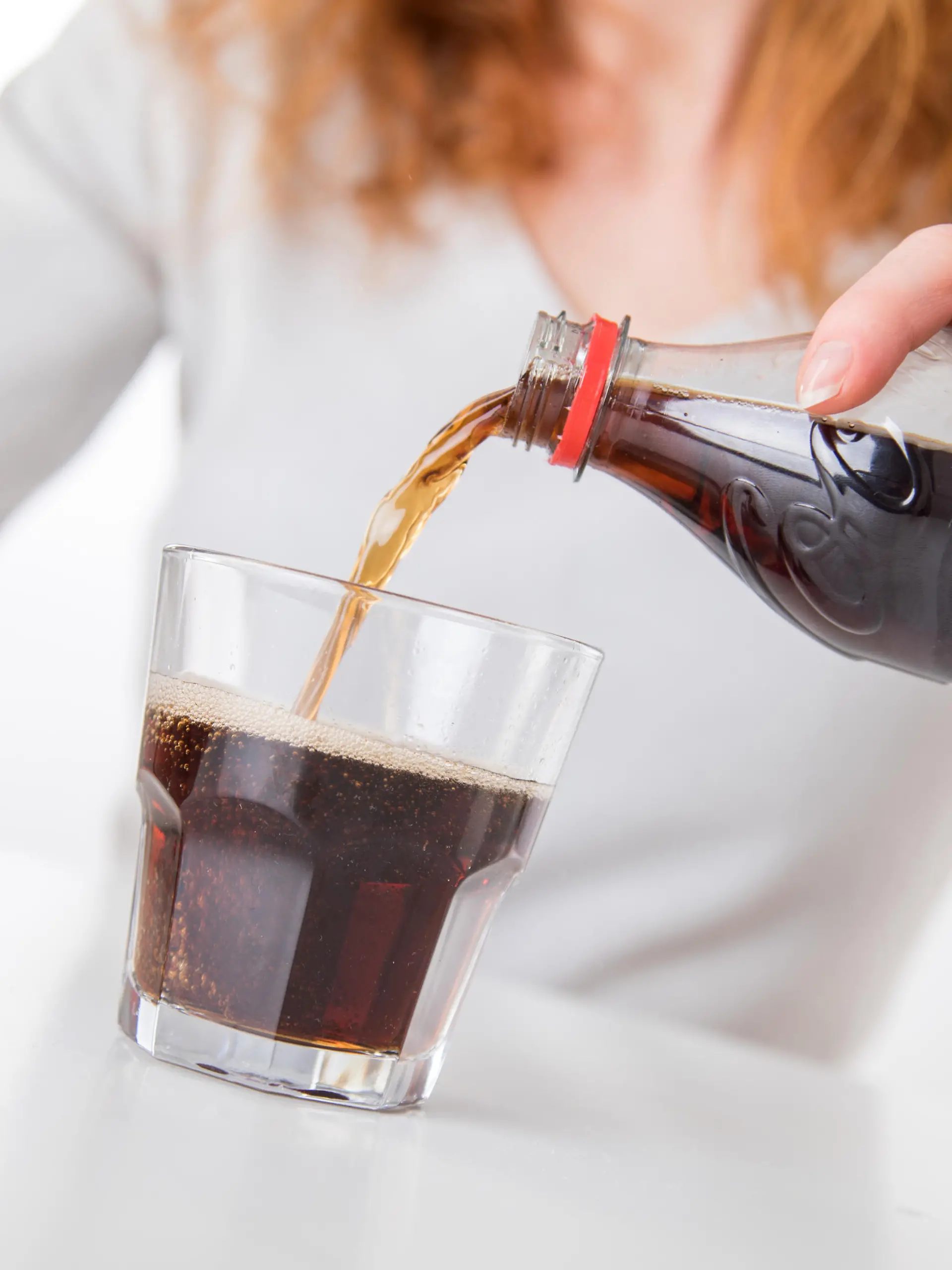 Frau gießt sich Cola in ein Glas