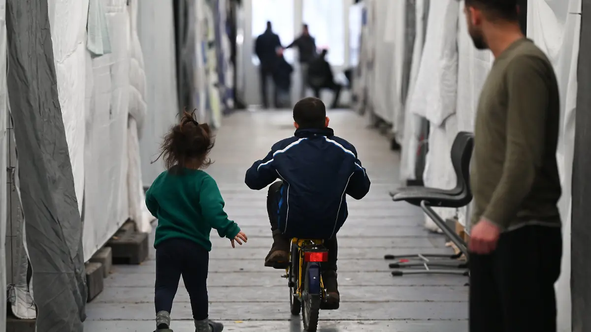 ARCHIV - 10.02.2023, Hessen, Bensheim: Flüchtlinge sind in einem der Zelte einer provisorischen Flüchtlingsunterkunft unterwegs. Am 30. März findet ein Kommunalgipfel der Unionsfraktion zur Asyl- und Flüchtlingspolitik statt. Thema sind die Probleme bei der Unterbringung von Flüchtlingen. Foto: Arne Dedert/dpa +++ dpa-Bildfunk +++