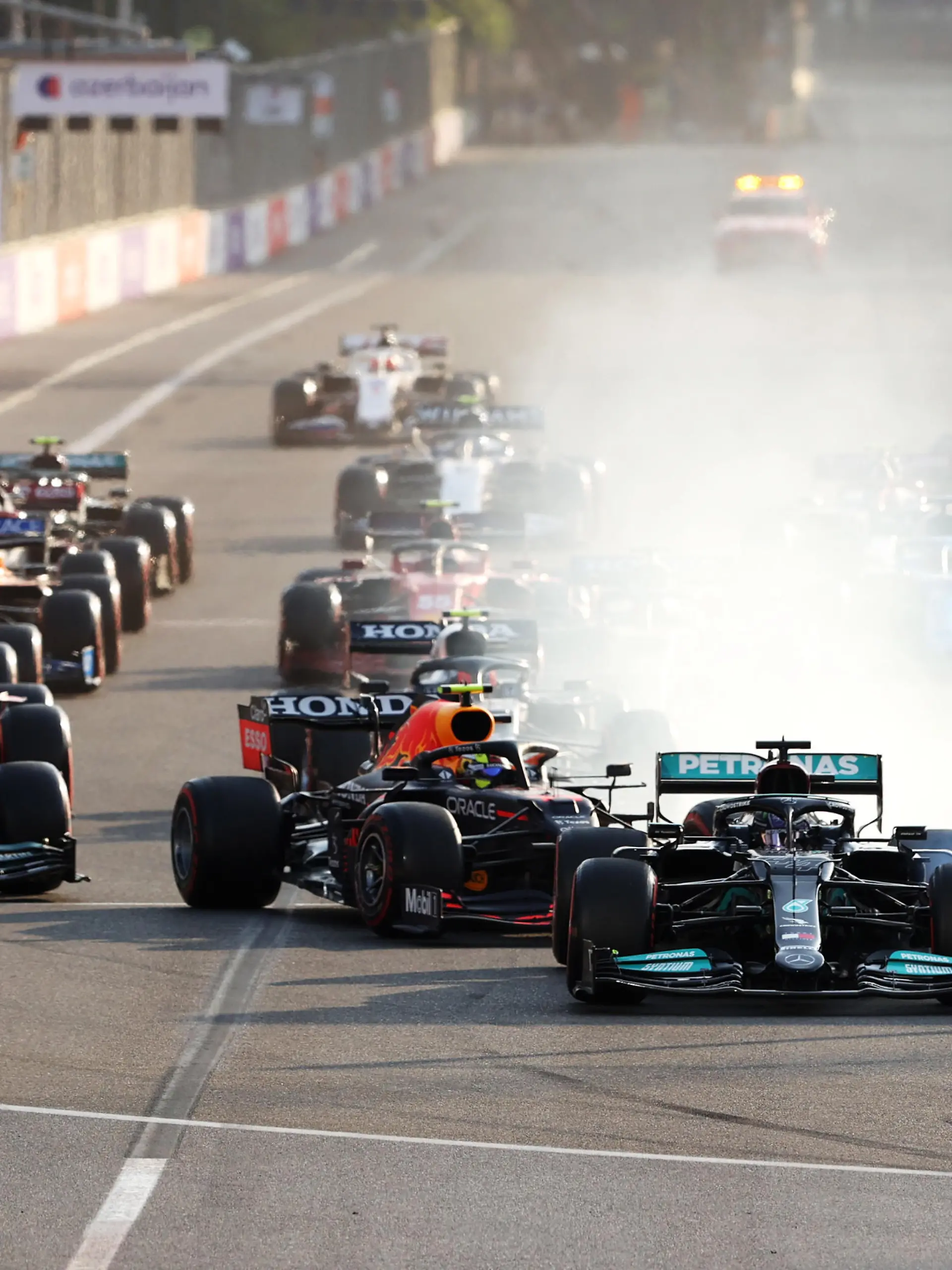 BAKU, AZERBAIJAN - JUNE 06: Lewis Hamilton of Great Britain driving the (44) Mercedes AMG Petronas F1 Team Mercedes W12 locks up under pressure from Sergio Perez of Mexico driving the (11) Red Bull Racing RB16B Honda into the first corner after the restart following a red flag period during the F1 Grand Prix of Azerbaijan at Baku City Circuit on June 06, 2021 in Baku, Azerbaijan. (Photo by Clive Rose/Getty Images)