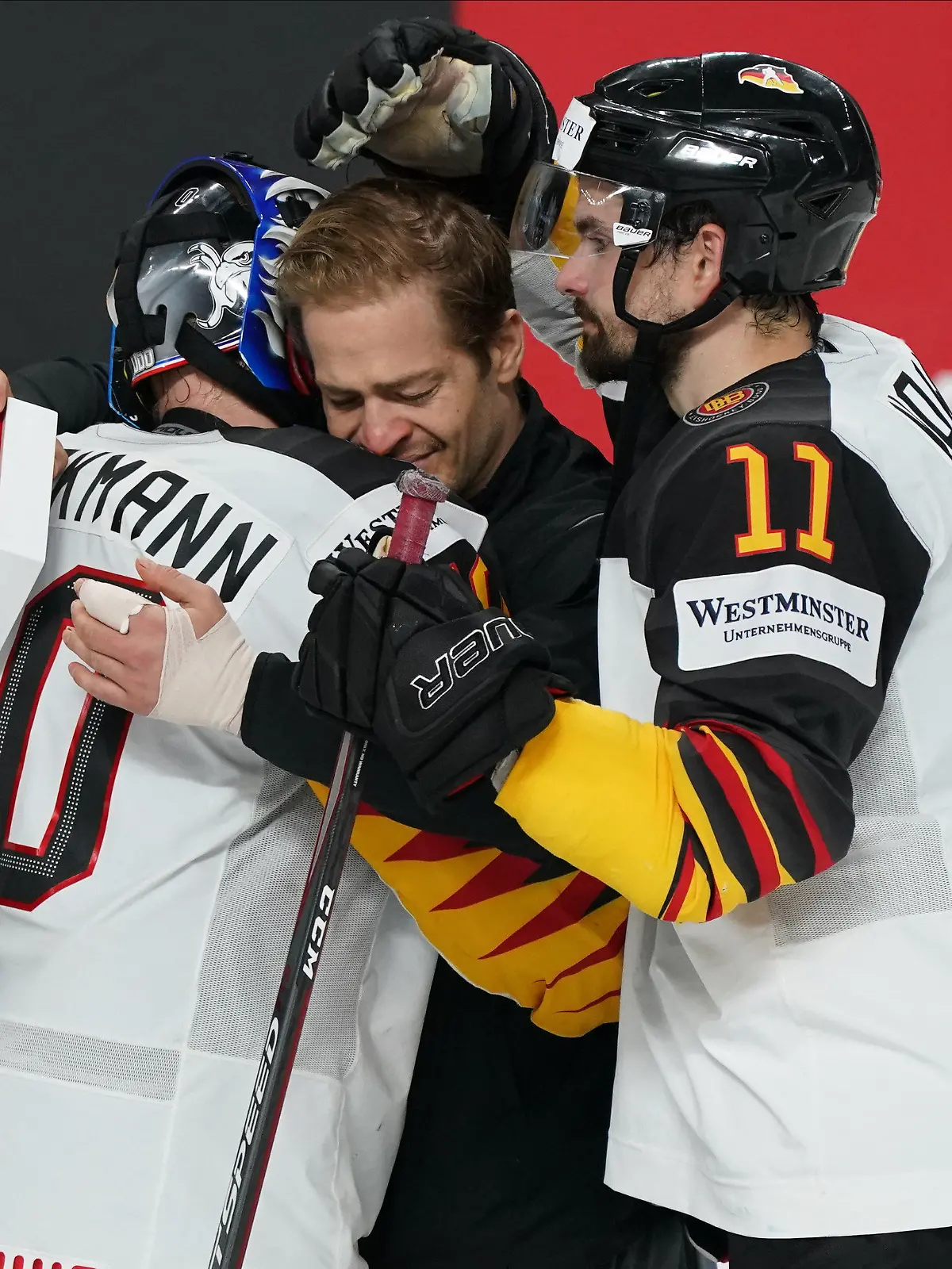 06.06.2021, Lettland, Riga: Eishockey: Weltmeisterschaft, Spiel um Platz 3, USA - Deutschland: Deutschlands Kapitän Moritz Müller (M) kommen bei der Umarmung mit Felix Brückmann und Marco Nowak die Tränen. Deutschland hat das Spiel um Platz drei gegen die USA mit 1:6 verloren. Foto: Roman Koksarov/dpa +++ dpa-Bildfunk +++