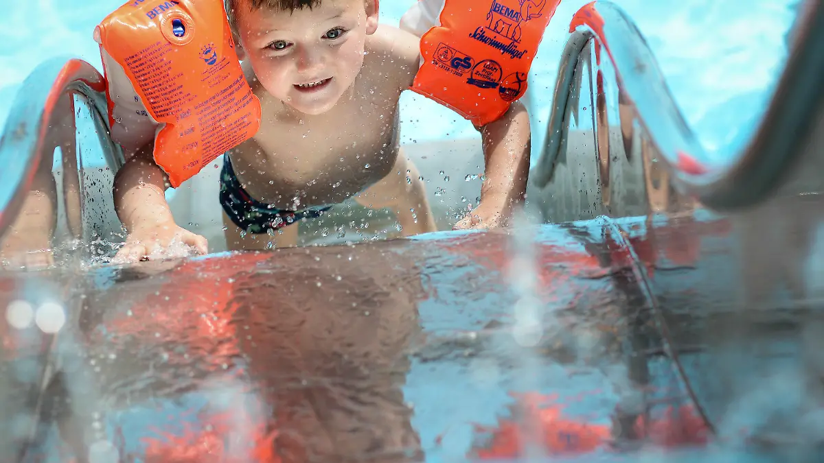 Der kleine Robin rutscht am 10.06.2014 mit seinen Schwimmflügeln im Freibad Gaustadt bei Bamberg (Bayern) ins kühle Nass. Foto: David Ebener/dpa +++(c) dpa - Bildfunk+++