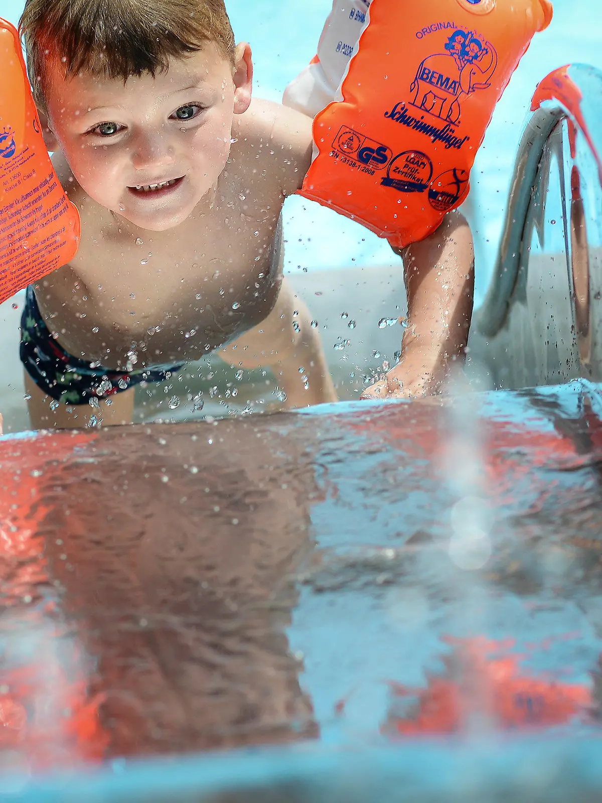 Der kleine Robin rutscht am 10.06.2014 mit seinen Schwimmflügeln im Freibad Gaustadt bei Bamberg (Bayern) ins kühle Nass. Foto: David Ebener/dpa +++(c) dpa - Bildfunk+++