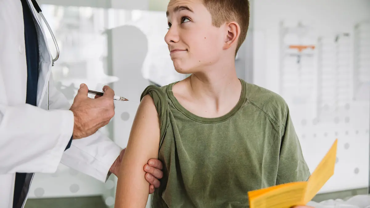 Doctor injecting a vaccine into teenagers arm model released Symbolfoto property released MFF05520