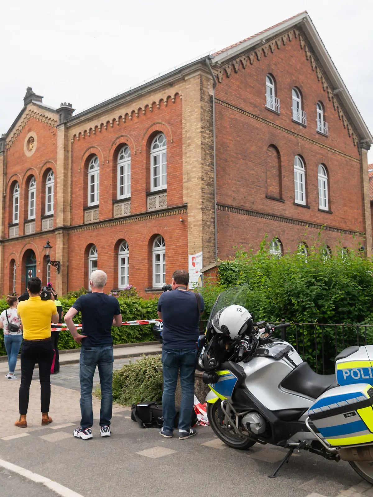 03.06.2021, Niedersachsen, Celle: Polizisten und Journalisten stehen vor dem Amtsgericht Celle. Auf dem Gelände des Amtsgerichts hat ein Mann eine Frau und anschließend sich selbst erschossen. Die Schüsse sind in der Nähe des Eingangs gefallen. Foto: Julian Stratenschulte/dpa +++ dpa-Bildfunk +++
