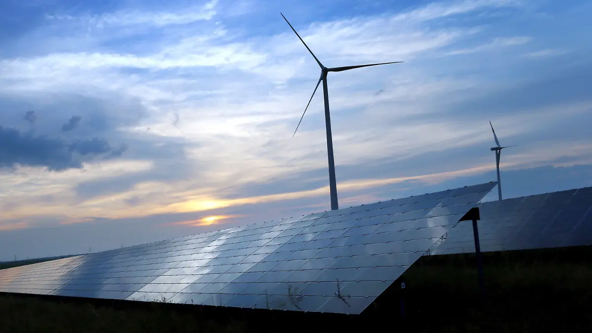ARCHIV - 06.06.2018, Bayern, Kitzingen: Der mit Wolken überzogene Abendhimmel spiegelt sich auf den Solarzellen einer vor Windrädern stehenden Solarkraftanlage (zu «Bund Naturschutz fordert rasche und konsequente Klimaschutz-Maßnahmen»). Foto: Karl-Josef Hildenbrand/dpa +++ dpa-Bildfunk +++