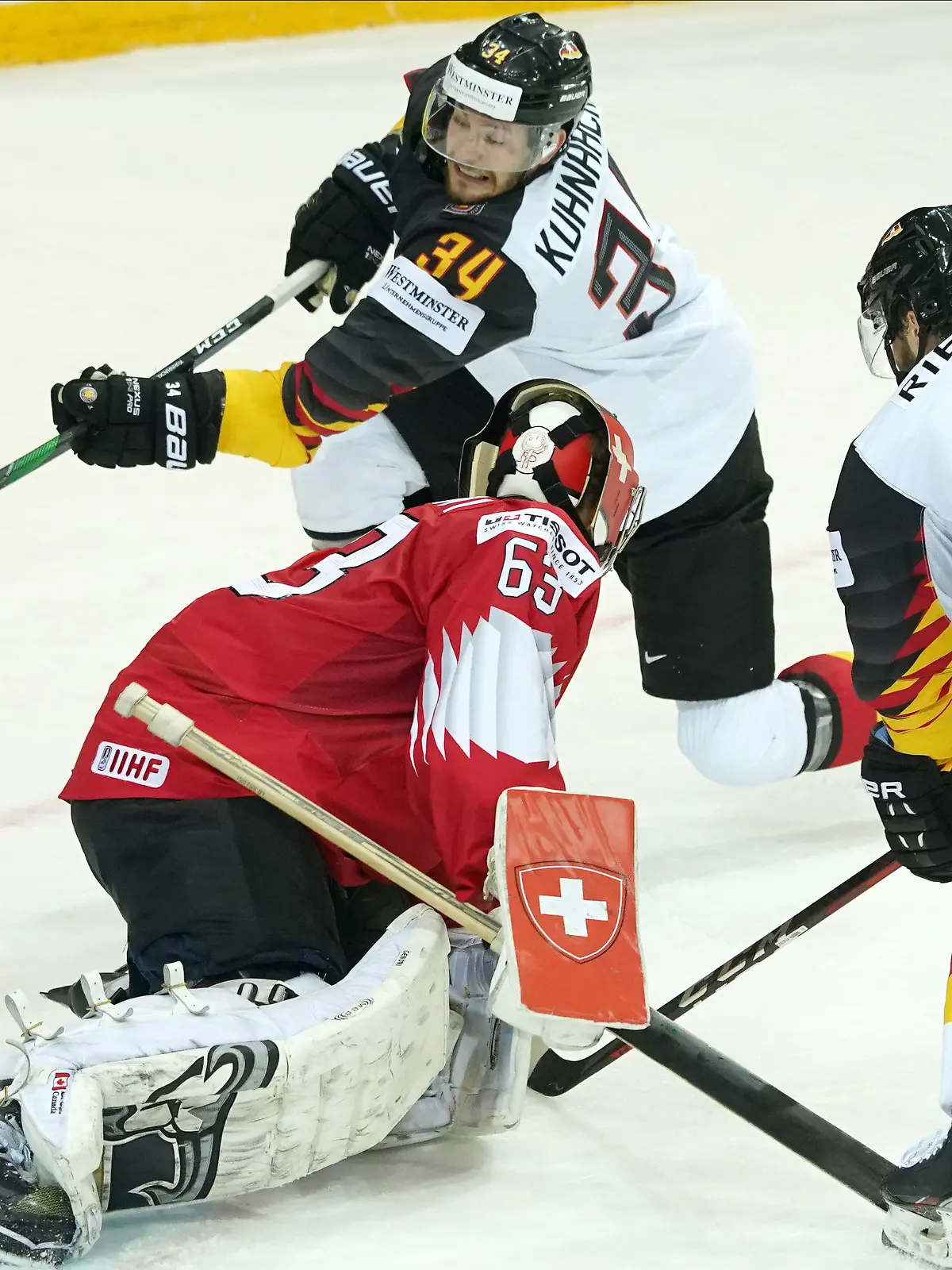 03.06.2021, Lettland, Riga: Eishockey: Weltmeisterschaft, Viertelfinale, Schweiz - Deutschland: Leonardo Genoni aus der Schweiz (M) kämpft vor dem Tor vor Deutschlands Tom Kühnhackl  (hinten) und Tobias Rieder (r). Foto: Roman Koksarov/dpa +++ dpa-Bildfunk +++