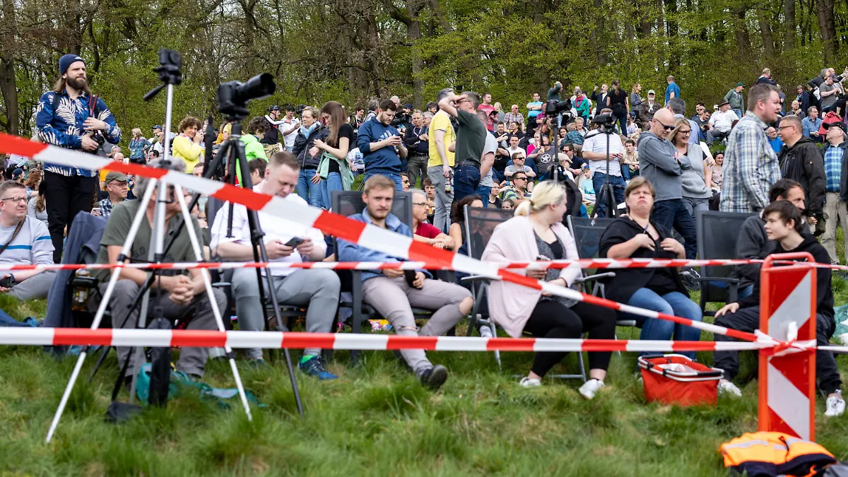 07.05.2023, Nordrhein-Westfalen, Lüdenscheid: Zahlreiche Zuschauer verfolgen die Sprengung der Talbrücke von einer Wiese auf einem Berg in der Nähe. Seit 17 Monaten ist die wichtige Autobahnbrücke gesperrt - mit gravierenden Folgen. Die Sprengung in bebautem Umfeld ist schwierig, das 17 000 Tonnen schwere Bauwerk muss akkurat aus bis zu 70 Metern Höhe auf ein Fallbett stürzen. Foto: Christoph Reichwein/dpa +++ dpa-Bildfunk +++
