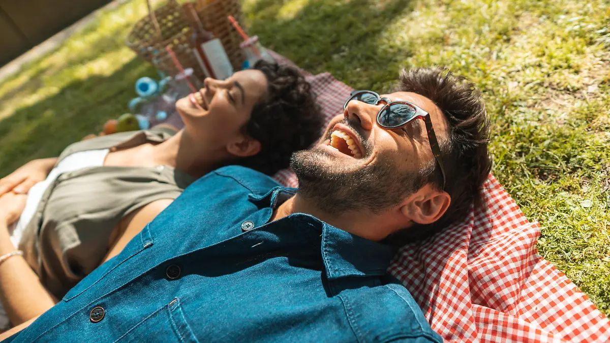 Mann und Frau liegen auf Picknick-Decke im Park