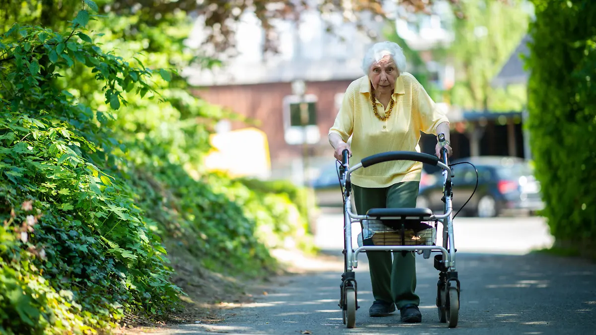02.06.2021, Nordrhein-Westfalen, Nottuln: Marietheres Wübken geht mit einem Rollator eine Straße entlang. Mit täglichen Rollator-Runden durch das münsterländische Nottuln sammelt die 97-Jährige Spenden für Schulkinder aus armen Ländern. Schon jetzt hat sie mit ihrem Ehrgeiz und ihrem Engagement das vierfache der ursprünglich vorgesehen Summe eingesammelt. (zu dpa «Rollator-Runden für den guten Zweck: 97-Jährige macht Spendenlauf») Foto: Jonas Güttler/dpa +++ dpa-Bildfunk +++