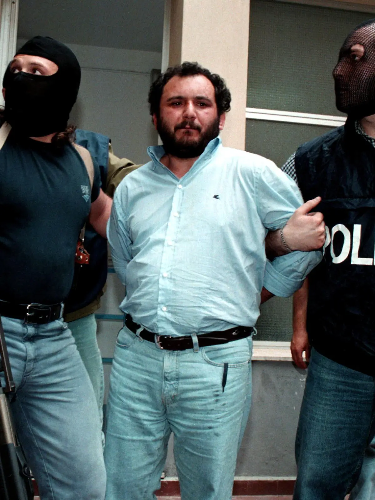 FILE PHOTO: Anti-Mafia police wearing masks to hide their identity, escort top Mafia fugitive Giovani Brusca May 21 as he leaves Palermo's police headquarters to be taken to a maximum security prison. Brusca, accused of mastermining the highway bombing that killed anti-mob judge Giovanni Falcone along with his wife and three bodyguards on May 23, 1992, and is also beleived to have succeeded Salvatore "Toto" Rina as the Mafia's boss of bosses, was arrested with his brother Vincenzo/File Photo
