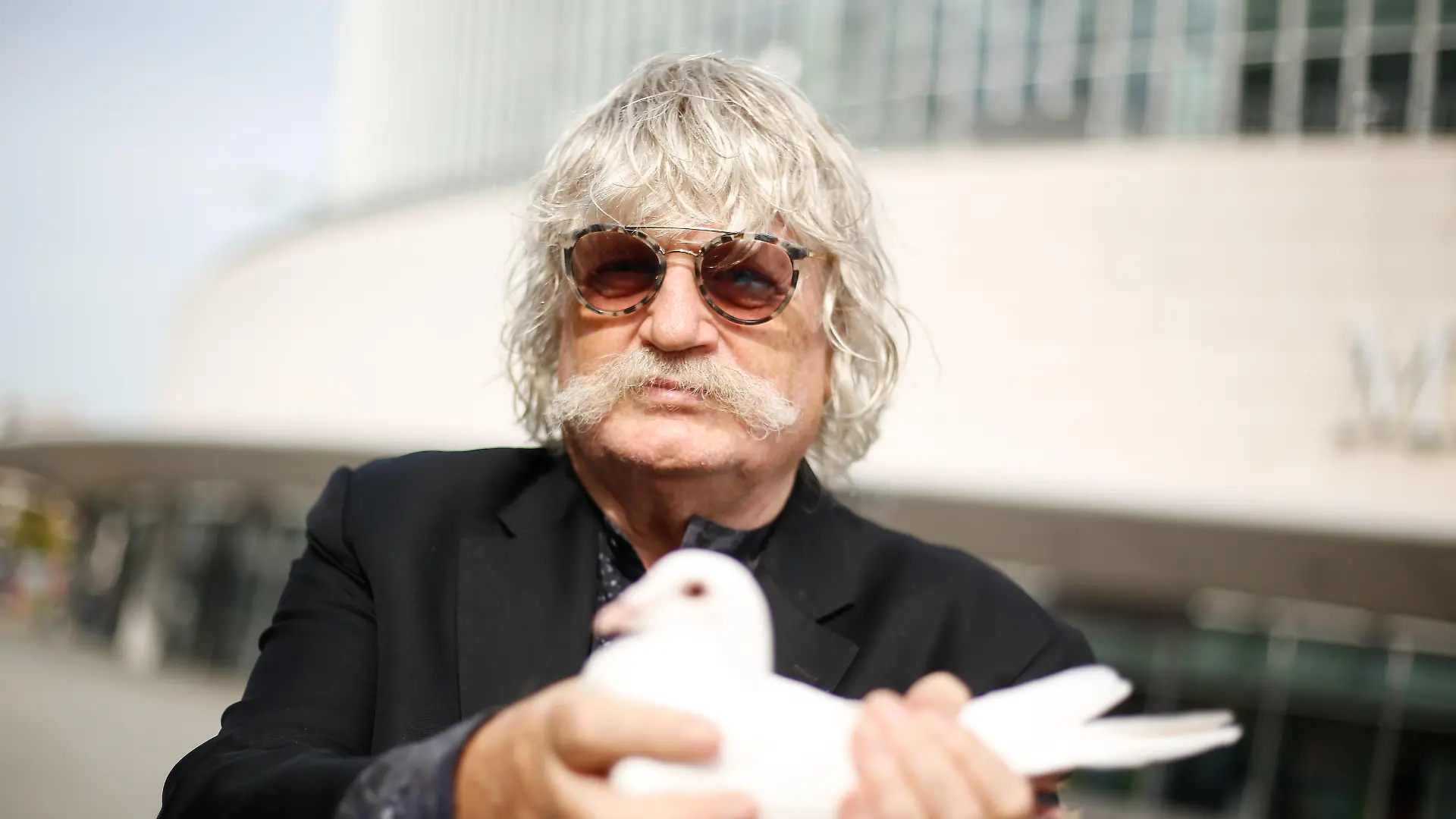 Komponist Sir Karl Jenkins hält eine Taube bei der Pressekonferenz zu "The Armed Man: A Mass for Peace" vor der Mercedes Benz Arena. Foto: Gerald Matzka/dpa-Zentralbild/ZB