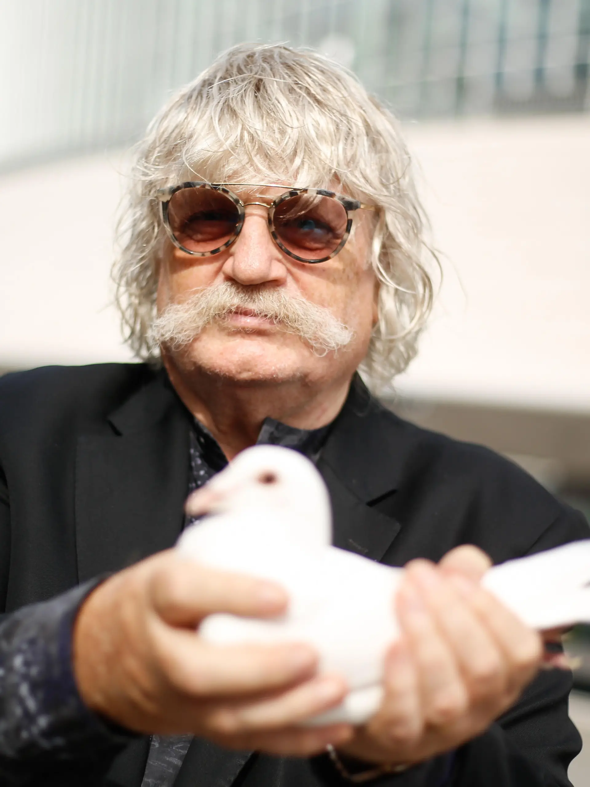 Komponist Sir Karl Jenkins hält eine Taube bei der Pressekonferenz zu "The Armed Man: A Mass for Peace" vor der Mercedes Benz Arena. Foto: Gerald Matzka/dpa-Zentralbild/ZB