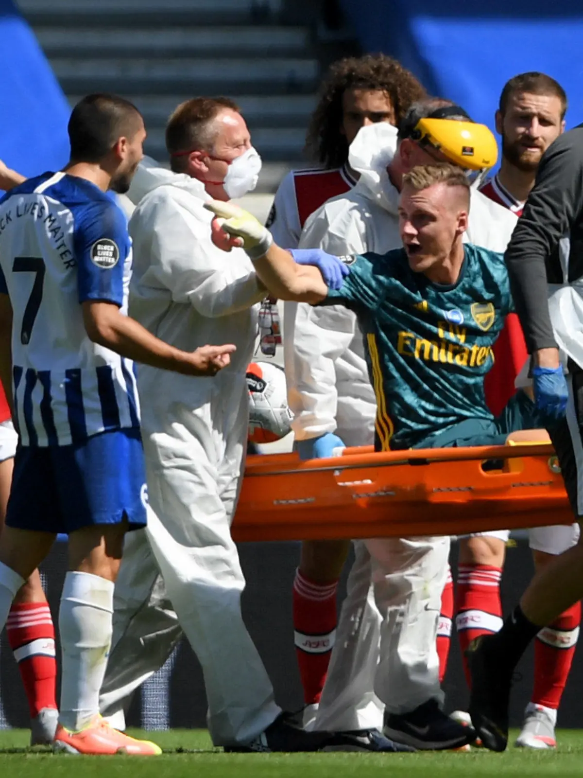 20.06.2020, Großbritannien, Brighton: Fußball: Premier League, England, Brighton & Hove Albion - FC Arsenal, 30. Spieltag, Amex Stadion: Der Torwart Bernd Leno (3.v.r) vom FC Arsenal zeigt auf Neal Maupay (4.v.l) von Brighton & Hove Albion, während er auf einer Trage vom Feld getragen wird. Foto: Mike Hewitt/Nmc Pool/PA Wire/dpa +++ dpa-Bildfunk +++