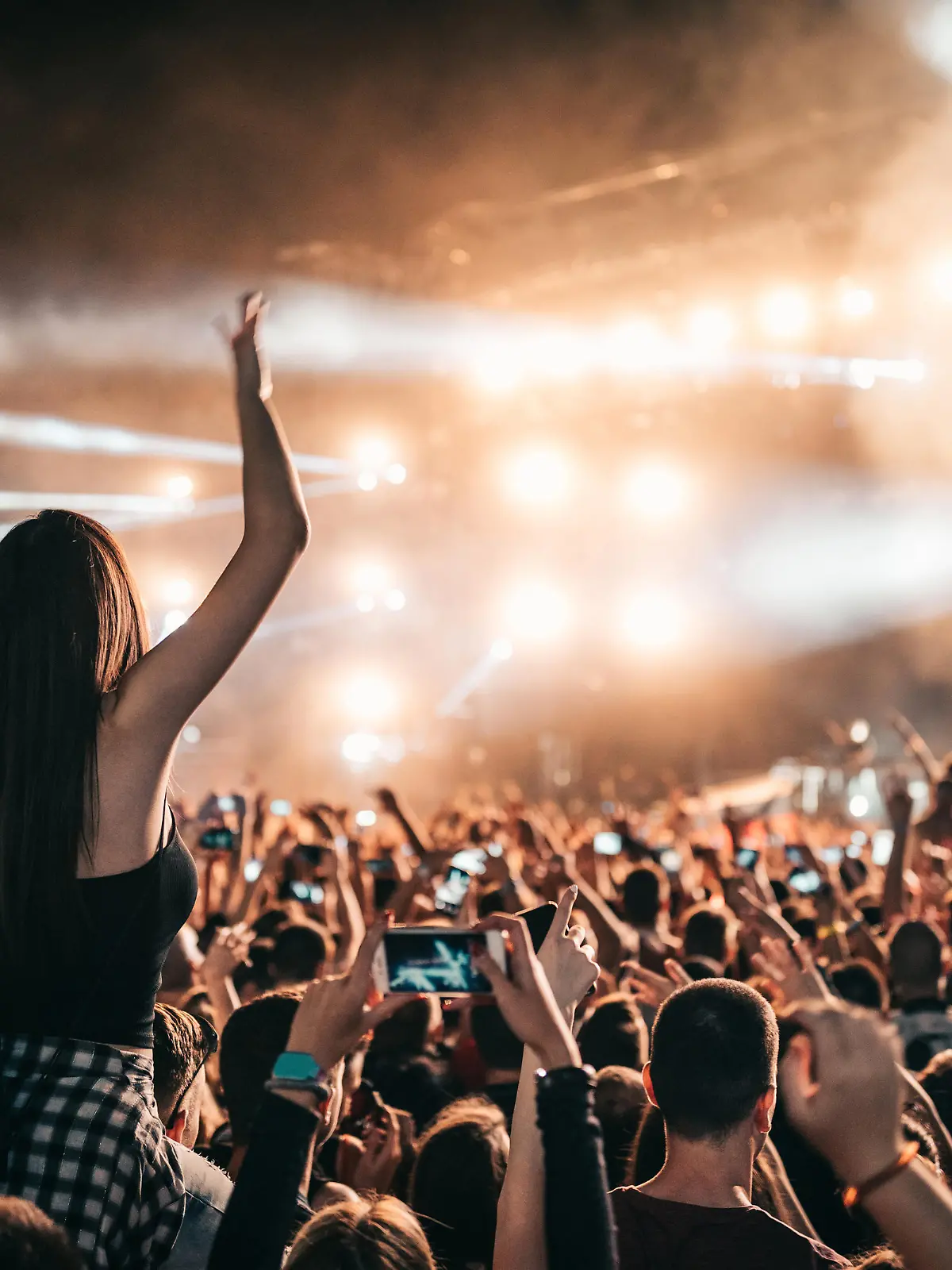 Ein großes Publikum auf einem Festival steht vor einer Bühne und feiert.
