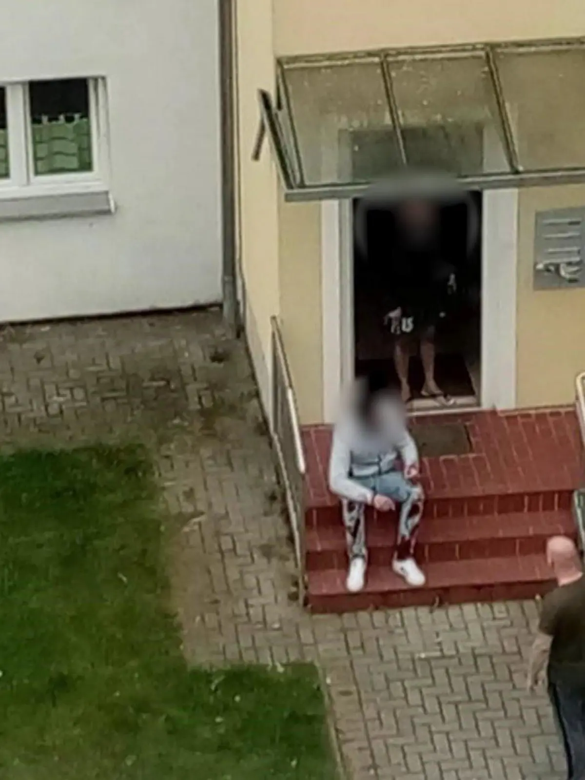 Der mutmaßliche Täter sitzt mit blutiger Hose unmittelbar nach der Tat vor dem Haus.