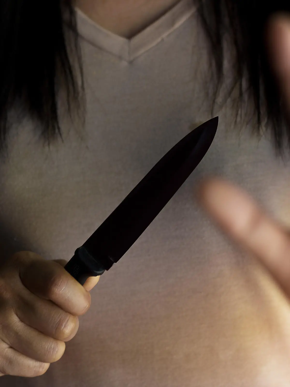Woman holding a knife in hand while defending herself from attacks.