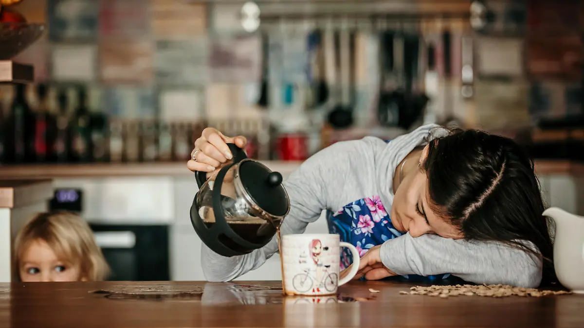 Übermüdete Mutter schüttet Kaffee in eine Tasse