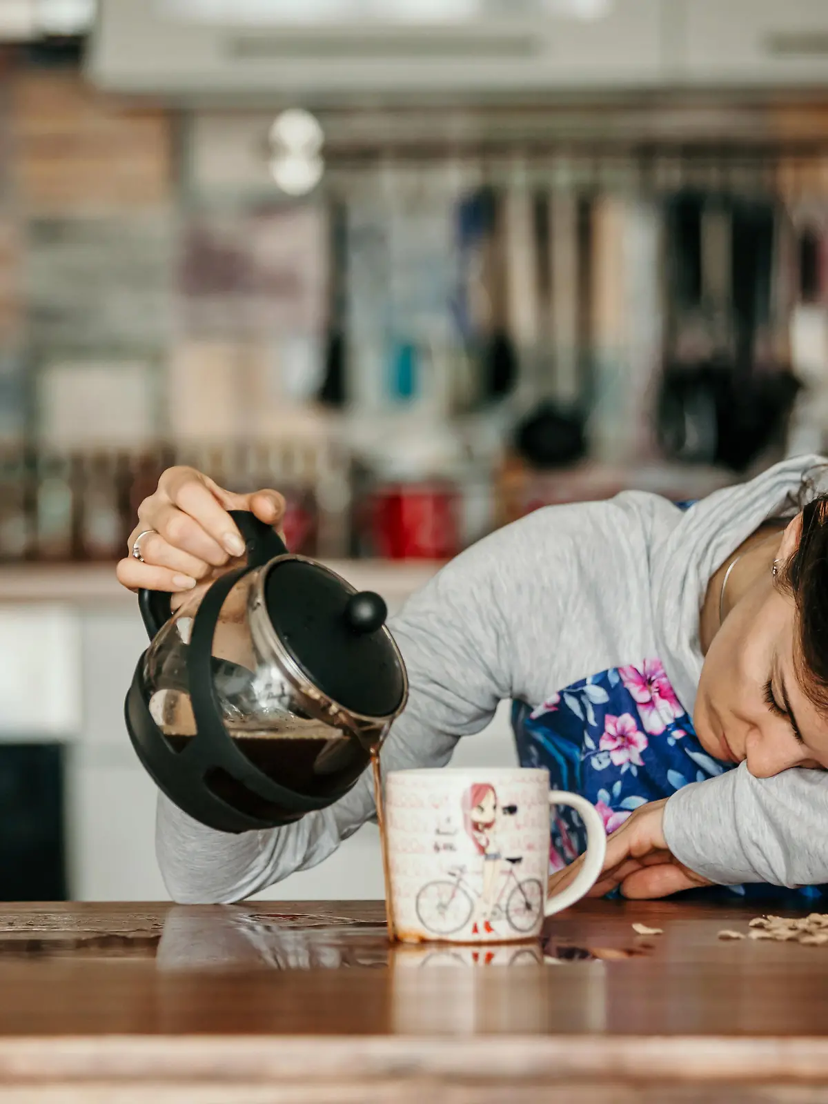 Übermüdete Mutter schüttet Kaffee in eine Tasse