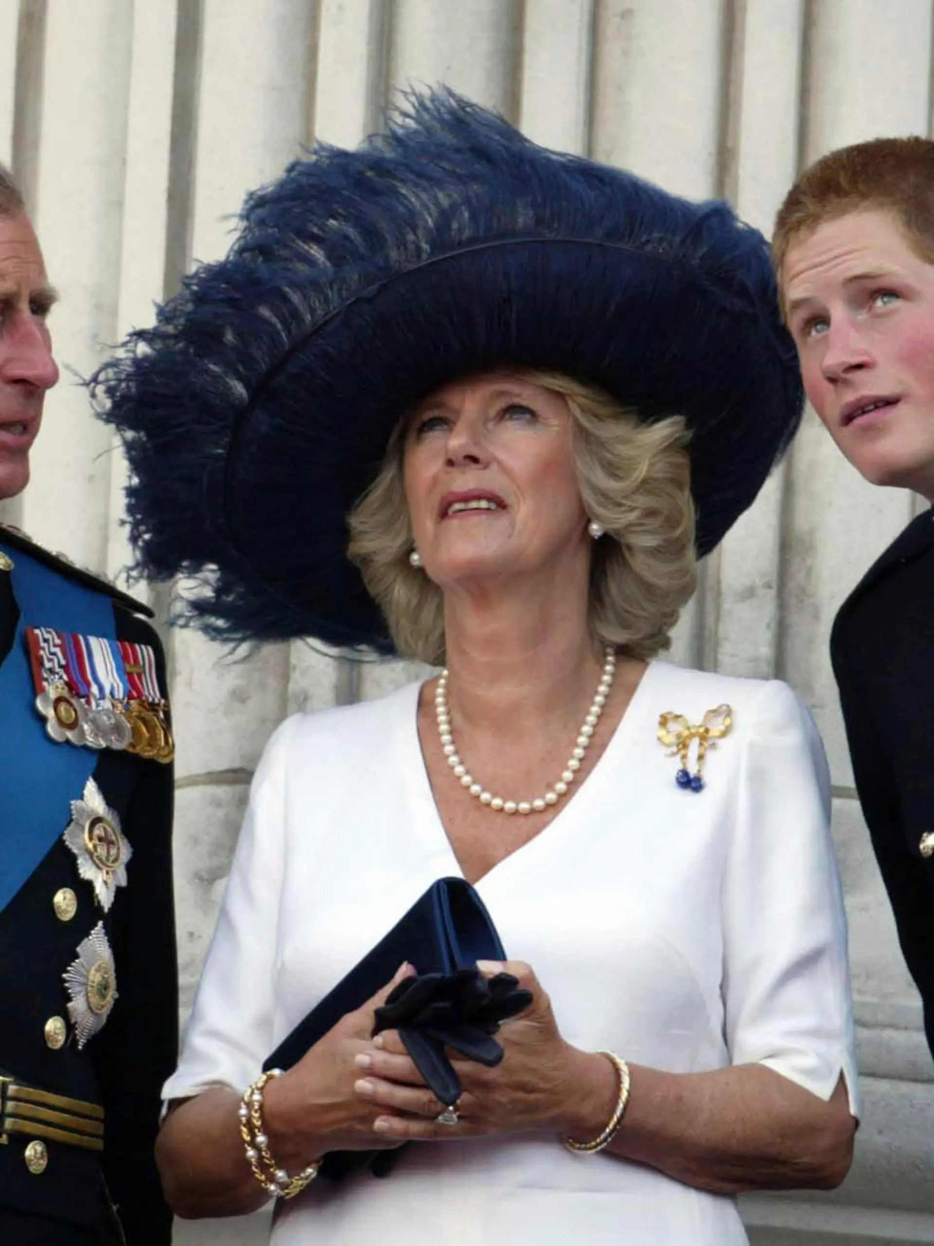 FILE - Britain's Prince Charles, Camilla, Duchess of Cornwall and Prince Harry, from left, watch as a Lancaster bomber drops one million poppies over The Mall, marking the end of WWII,  from the balcony of Buckingham Palace, London, Sunday July 10, 2005. Britain's queen consort, Camilla, has come a long way. On May 6, she will be crowned alongside her husband and officially take her first turns on the world stage as Queen Camilla. It’s been a remarkable and painstakingly slow transformation over five decades.  (James Vellacott, Pool Photo via AP, File)
