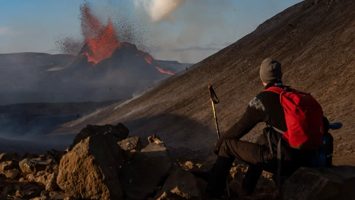 A man watches as lava spews from an eruption of the Fagradalsfjall volcano on the Reykjanes Peninsula in southwestern Iceland on Tuesday, May 11, 2021. (AP Photo/Miguel Morenatti)