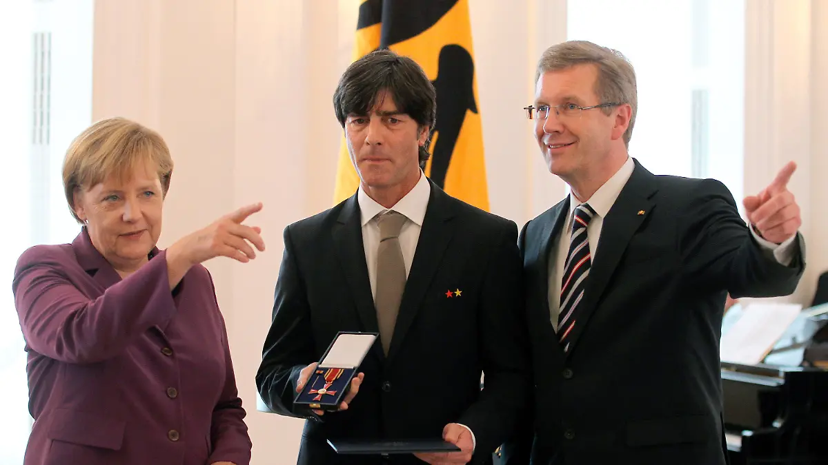 Bundestrainer Joachim Löw (M) bekommt am Dienstag (05.10.2010) im Schloss Bellevue in Berlin das Bundesverdienstkreuz von Bundespräsidenten Christian Wulff (r)(CDU) übergeben. Links steht Bundeskanzlerin Angela Merkel (CDU). Das deutsche Team und Bundestrainer Joachim Löw werden vom Bundespräsidenten Christian Wulff (CDU) für ihren dritten Platz bei der Fußball-Weltmeisterschaft in Südafrika geehrt. Löw ewrhält den Verdienstorden der Bundesrepublik Deutschland erhalten und die Spieler mit dem Silbernen Lorbeerblatt ausgezeichnet werden. Foto: Wolfgang Kumm dpa/lbn +++(c) dpa - Bildfunk+++