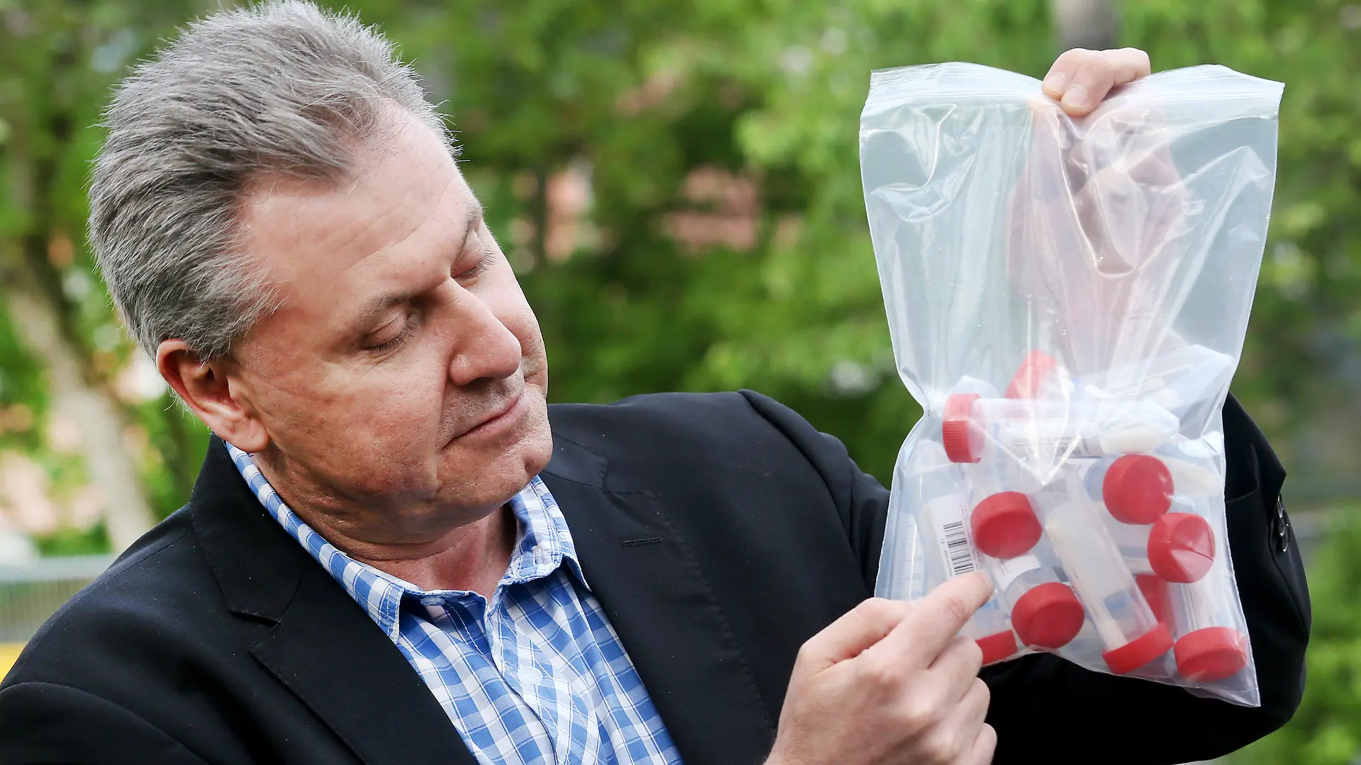 10.05.2021, Nordrhein-Westfalen, Essen: Udo Moter, Schulleiter der Maria-Kunigunda-Grundschule, zeigt die Sammelbehälter der "Lolli-Tests". Nordrhein-Westfalen führt am Montag sogenannte Lolli-Tests flächendeckend an allen Grund- und Förderschulen ein. Mit dem Test sollen alle mehr als 730 000 Schülerinnen und Schüler der knapp 3800 Grund- und Förderschulen zwei Mal pro Woche in ihrer jeweiligen Lerngruppe auf das Coronavirus getestet werden. Foto: Roland Weihrauch/dpa - ACHTUNG: Nur zur redaktionellen Verwendung im Zusammenhang mit der aktuellen Berichterstattung über die Einführung der Tests in den Schulen in NRW. +++ dpa-Bildfunk +++