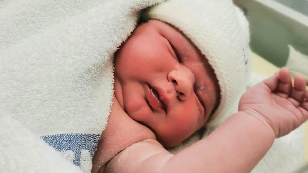 Man sieht ein Baby gehüllt in ein Handtuch.