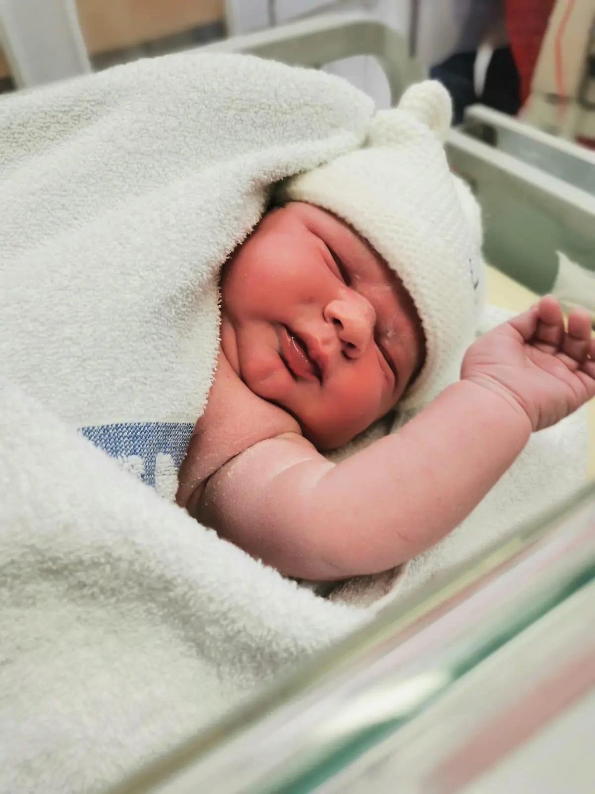 Man sieht ein Baby gehüllt in ein Handtuch.