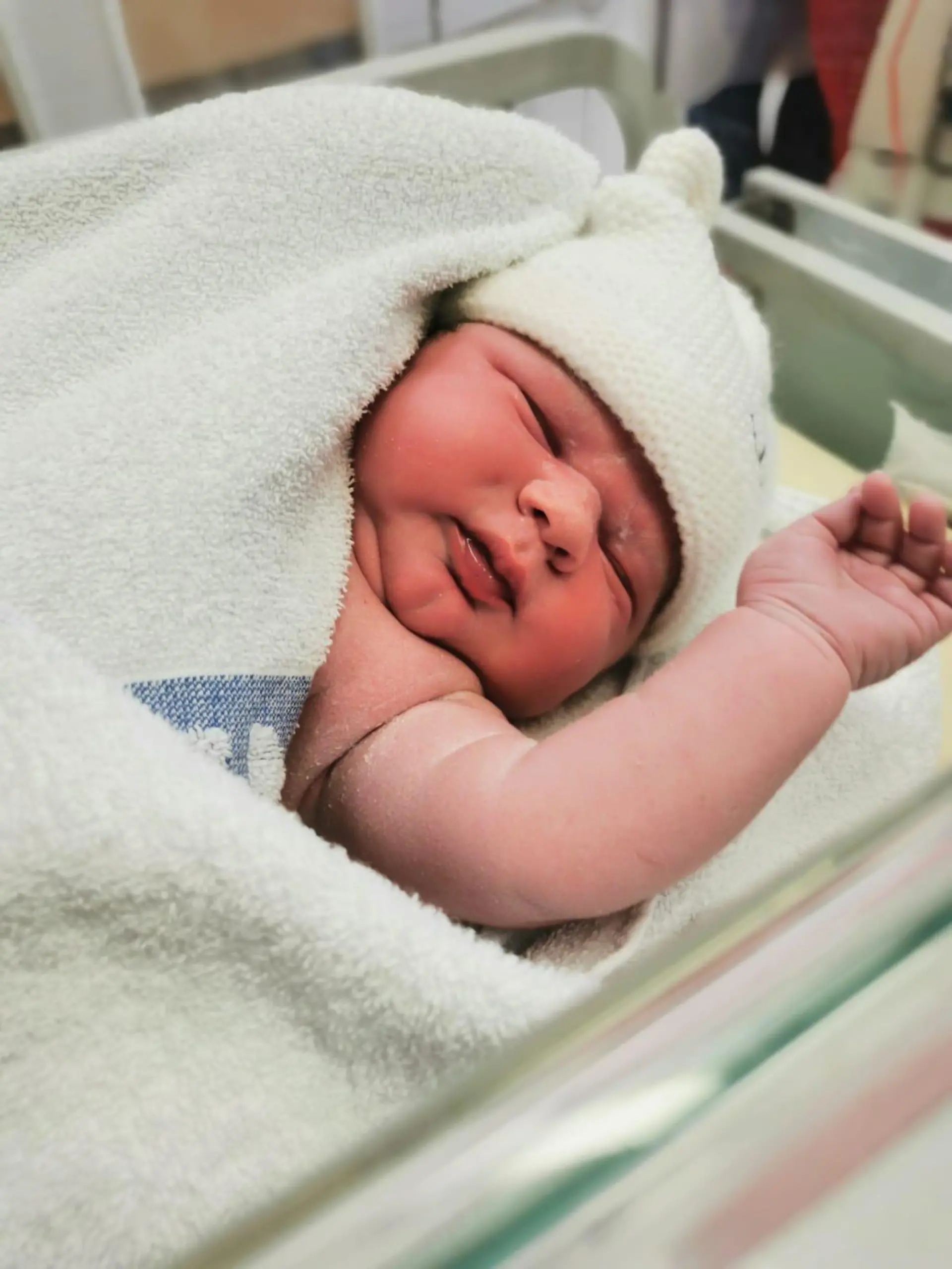 Man sieht ein Baby gehüllt in ein Handtuch.