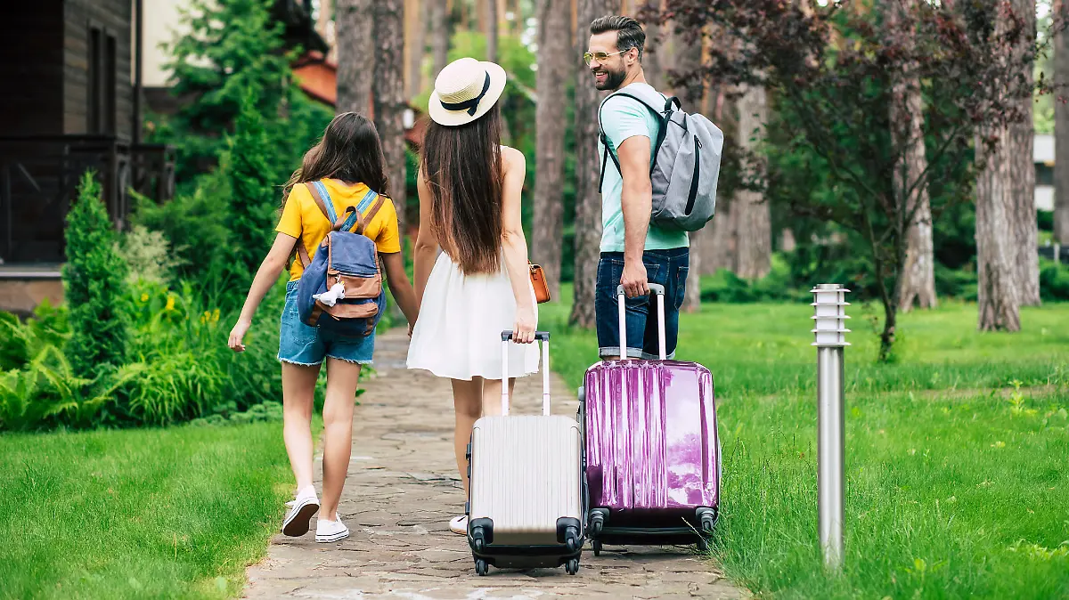 Familie mit Rollkoffern kommt an der Urlaubsunterkunft an