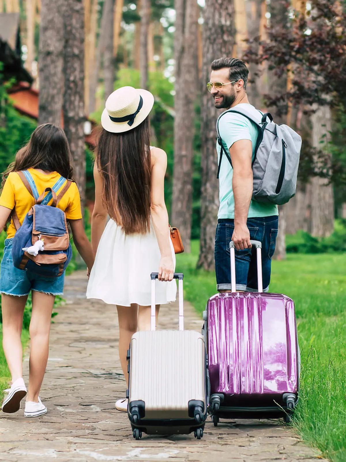 Familie mit Rollkoffern kommt an der Urlaubsunterkunft an