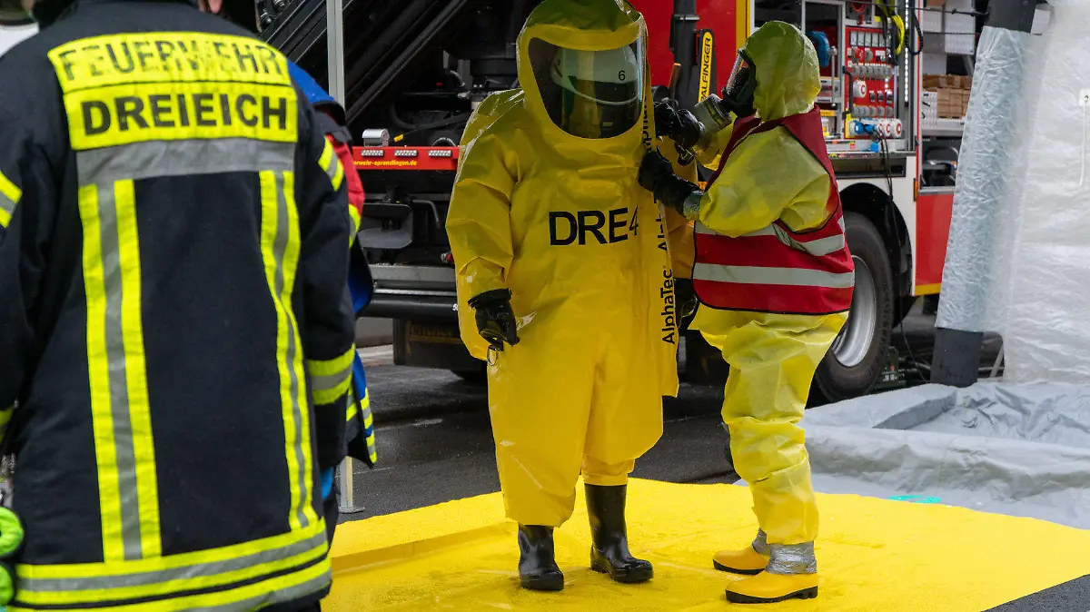 27.05.2021, Hessen, Dreieich: Feuerwehrleute stehen in ihren Schutzanzügen auf einer Dekontaminationsstraße. Bei einem Unfall auf einem Industriegelände  sind ein Mitarbeiter und zwei Feuerwehrleute verletzt worden. Ursache war der Austritt von Ammoniak, wie ein Sprecher der Feuerwehr im Kreis Offenbach berichtete. Foto: news@5vision.media/dpa +++ dpa-Bildfunk +++