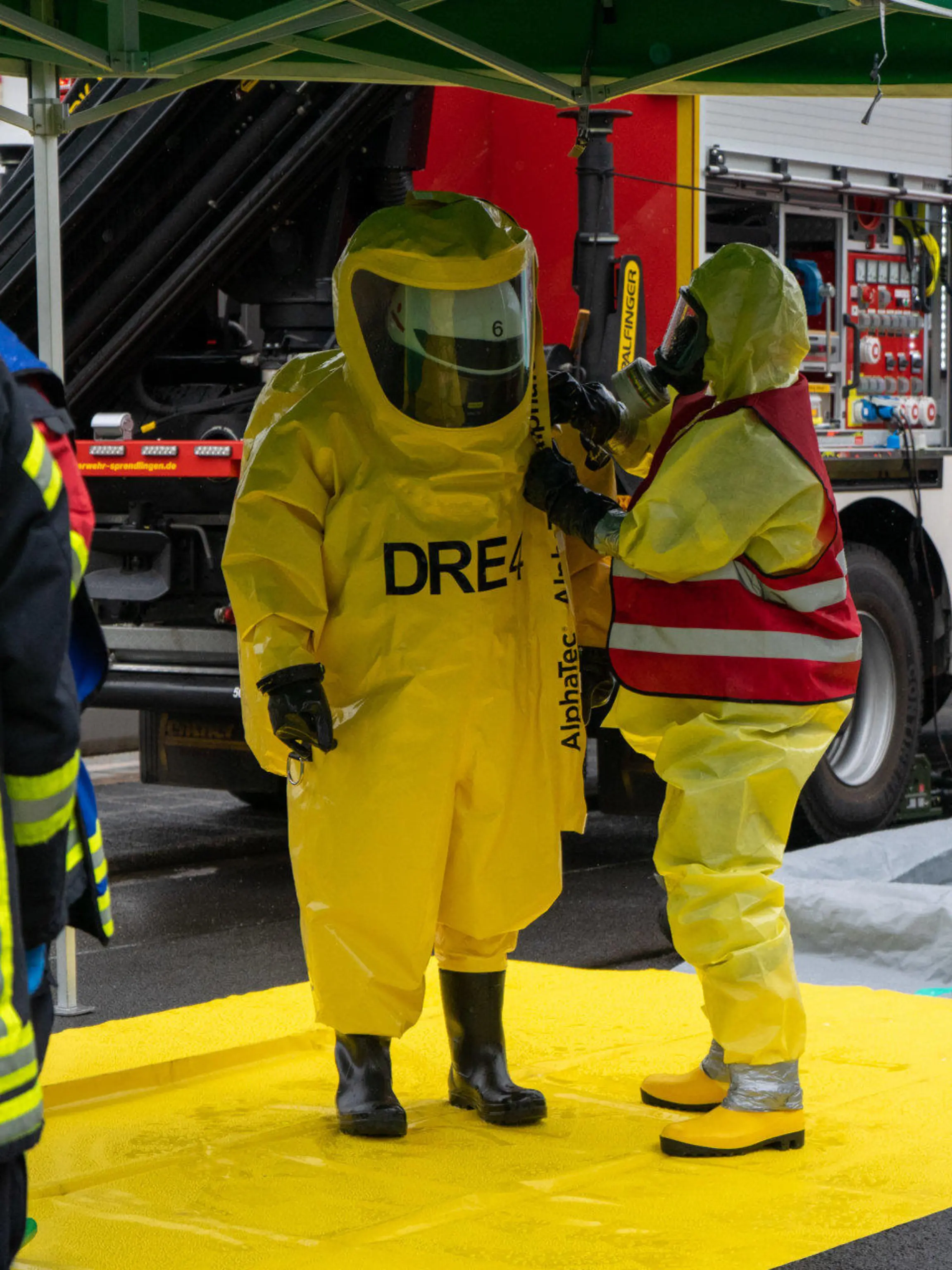 27.05.2021, Hessen, Dreieich: Feuerwehrleute stehen in ihren Schutzanzügen auf einer Dekontaminationsstraße. Bei einem Unfall auf einem Industriegelände  sind ein Mitarbeiter und zwei Feuerwehrleute verletzt worden. Ursache war der Austritt von Ammoniak, wie ein Sprecher der Feuerwehr im Kreis Offenbach berichtete. Foto: news@5vision.media/dpa +++ dpa-Bildfunk +++