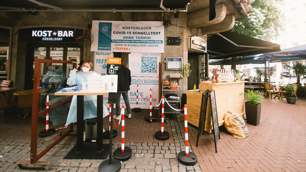 Mann vor Düsseldorfer Testzentrum neben Bar/Restaurant