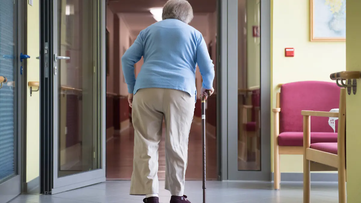 ARCHIV - 10.05.2019, Sachsen, Bernsdorf: Eine Frau geht in einem Pflegeheim an einem Gehstock. Private Pflegeanbieter warnen vor einer dramatischen Unterversorgung mit Kurzzeitpflegeplätzen in vielen Regionen. «Kurzfristig einen Platz zu finden, geht kaum», sagte der Leiter der Landesgeschäftsstelle des Bundesverbands privater Anbieter sozialer Dienste e.V., Grote, der Deutschen Presse-Agentur. Foto: Sebastian Kahnert/zb/dpa +++ dpa-Bildfunk +++