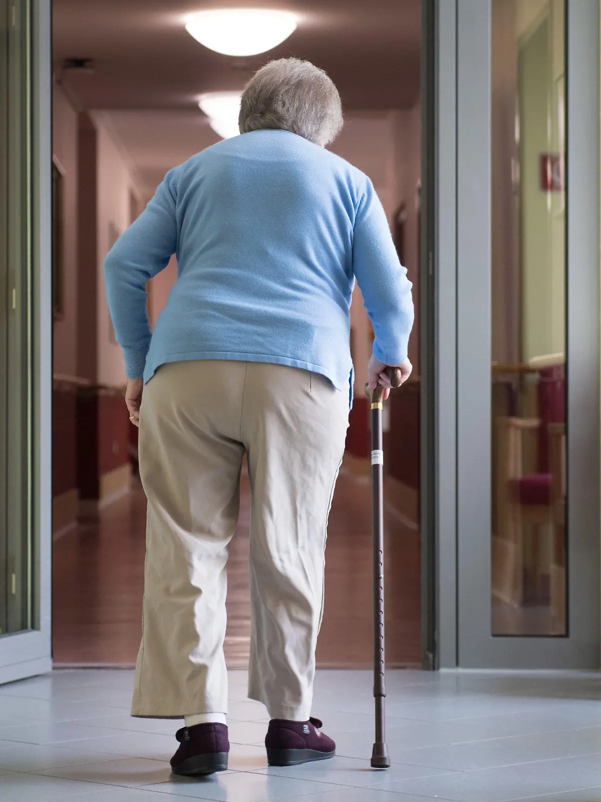 ARCHIV - 10.05.2019, Sachsen, Bernsdorf: Eine Frau geht in einem Pflegeheim an einem Gehstock. Private Pflegeanbieter warnen vor einer dramatischen Unterversorgung mit Kurzzeitpflegeplätzen in vielen Regionen. «Kurzfristig einen Platz zu finden, geht kaum», sagte der Leiter der Landesgeschäftsstelle des Bundesverbands privater Anbieter sozialer Dienste e.V., Grote, der Deutschen Presse-Agentur. Foto: Sebastian Kahnert/zb/dpa +++ dpa-Bildfunk +++