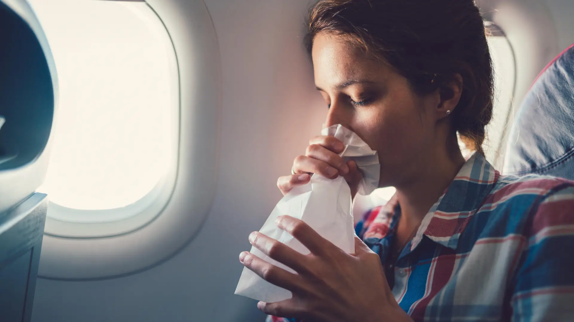 Frau atmet in Tüte im Flugzeug