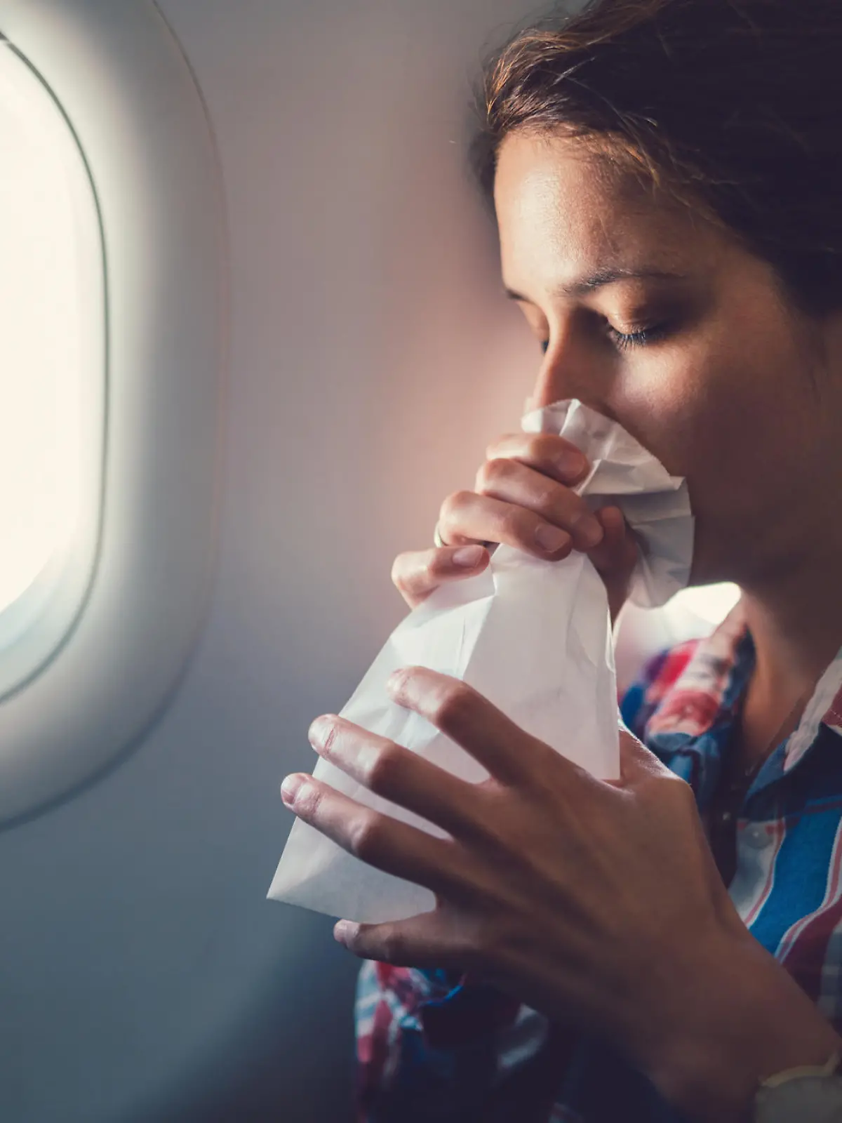 Frau atmet in Tüte im Flugzeug