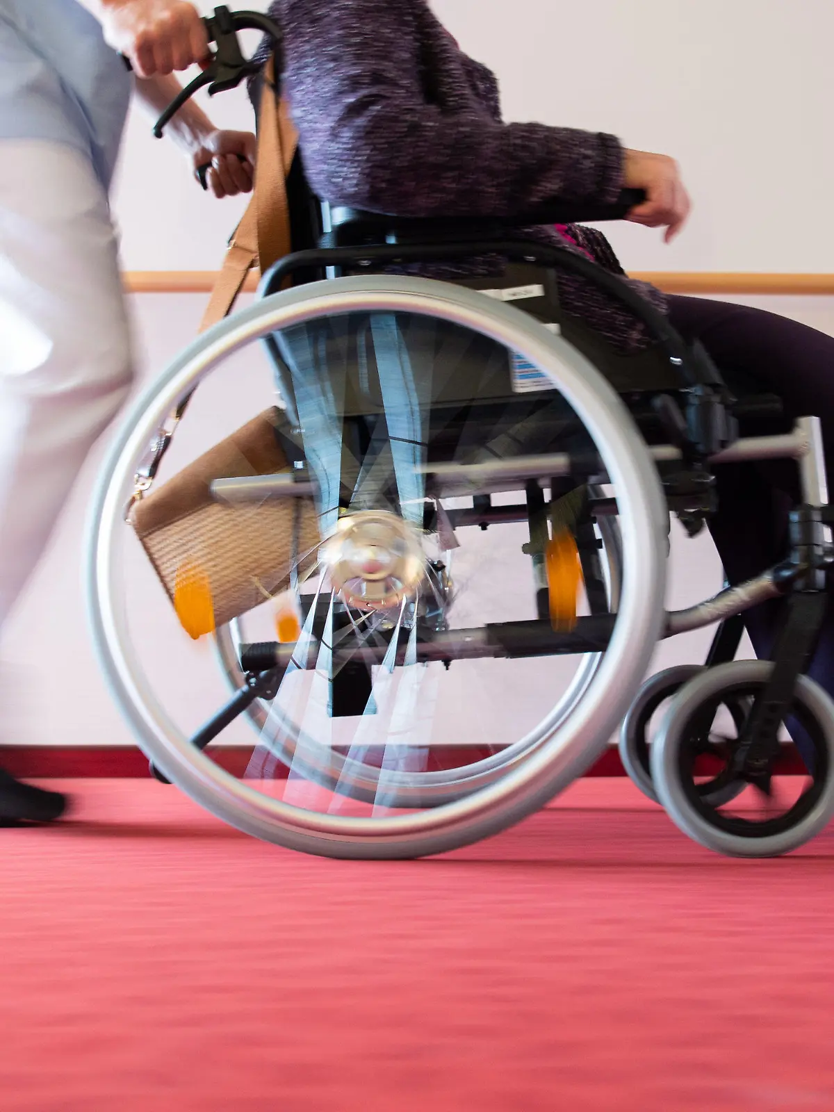 ARCHIV - 15.01.2020, Baden-Württemberg, Böblingen: Ein Pfleger schiebt eine Bewohnerin eines Pflegeheims in einem Rollstuhl über den Flur. Zum internationalen Tag der Pflege am 12. Mai demonstrieren Pflegende mit vielfältigen Aktionen für bessere Arbeitsbedingungen. (zu dpa «Pfleger protestieren im Südwesten für bessere Arbeitsbedingungen») Foto: Tom Weller/dpa +++ dpa-Bildfunk +++