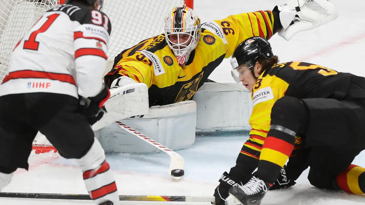Canada's Cole Perfetti, left, challenges for the puck with Germany's goaltender Mathias Niederberger, centre, and Germany's Moritz Seider during the Ice Hockey World Championship group B match between Germany and Canada at the Arena in Riga, Latvia, Monday, May 24, 2021. (AP Photo/Sergei Grits)