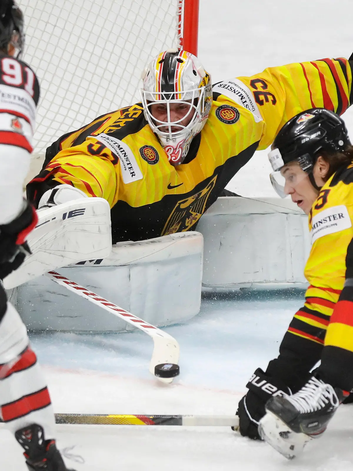 Canada's Cole Perfetti, left, challenges for the puck with Germany's goaltender Mathias Niederberger, centre, and Germany's Moritz Seider during the Ice Hockey World Championship group B match between Germany and Canada at the Arena in Riga, Latvia, Monday, May 24, 2021. (AP Photo/Sergei Grits)